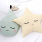 Decorative pillows shaped like a pear and a star with facial features on a white blanket