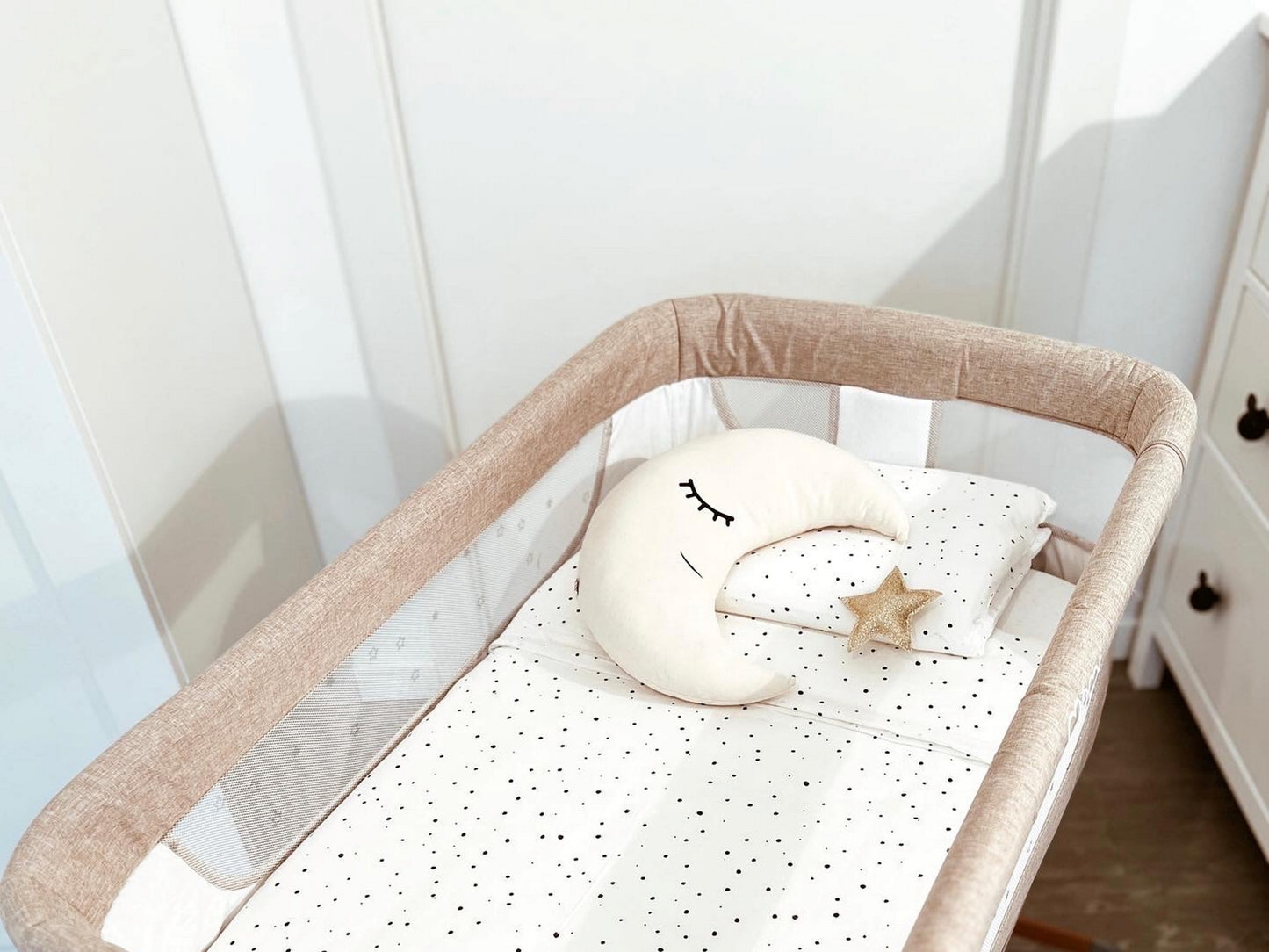 Baby crib with a moon-shaped pillow and star toy in a nursery setting