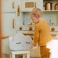 Child playing with a cloud-shaped stool in a kitchen setting
