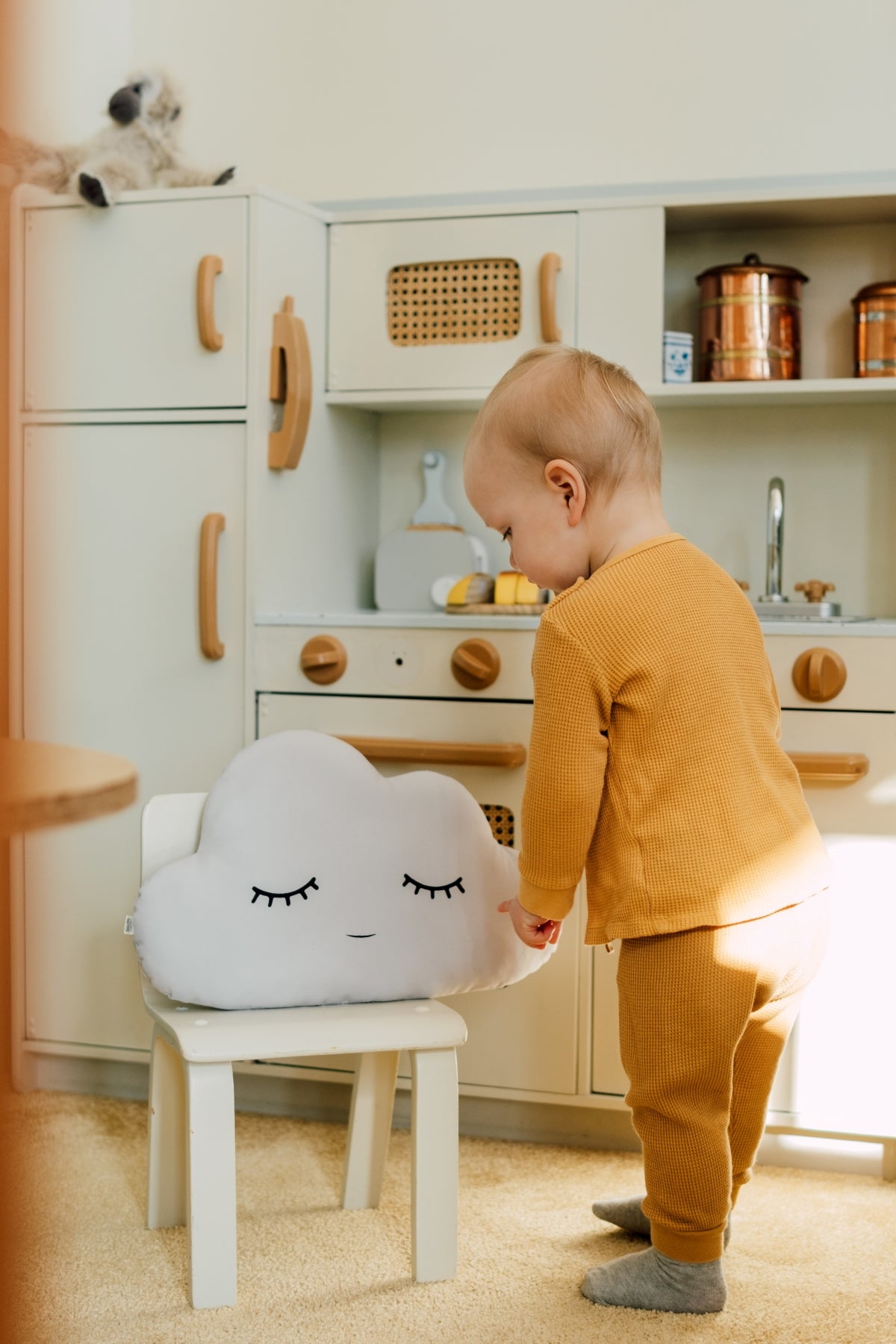 Child playing with a cloud-shaped stool in a kitchen setting