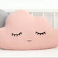 Pink cloud throw pillow, closed eyes and subtle smile – on bed beside gray version.