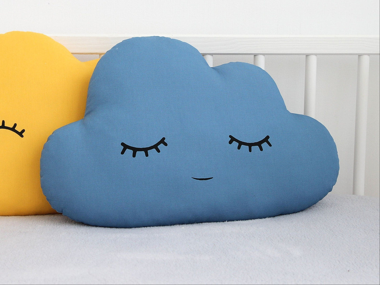 Petrol blue cloud-shaped throw pillow, closed eyes and gentle smile – on a childs bed or nursery decor.