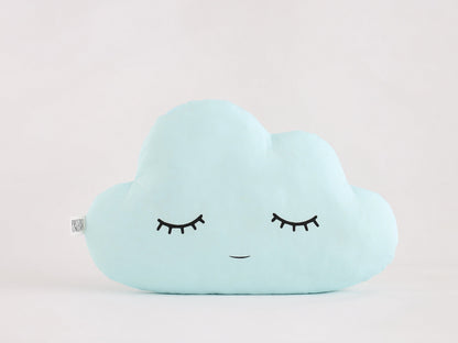 Light blue cloud-shaped throw pillow, closed eyes and small smile – plain white background.