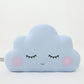 Light blue cloud throw pillow, closed eyes and blushing cheeks – on white background.