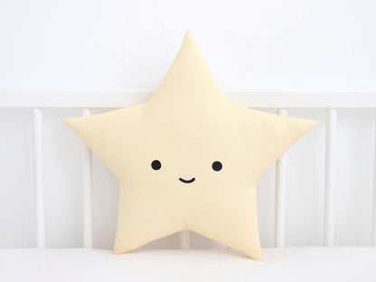 Pastel yellow star throw pillow, sweet smile – resting against white crib railing.
